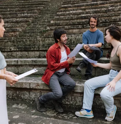 Paula Sanz guía un grupo de actores con guiones en un anfiteatro al aire libre durante una sesión de coaching (Terapia Escénica).