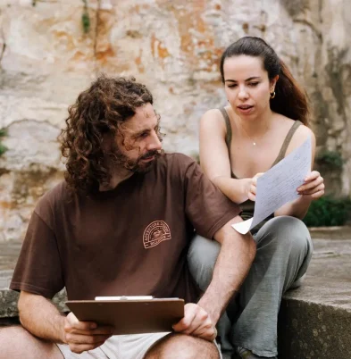 Paula Sanz conversa con un estudiante con guion en un espacio exterior, revisando una escena y acompañando el proceso en escuela de Arte Dramático (Terapia Escénica). Título: Terapia Escénica para escuelas de Arte Dramático Paula Sanz