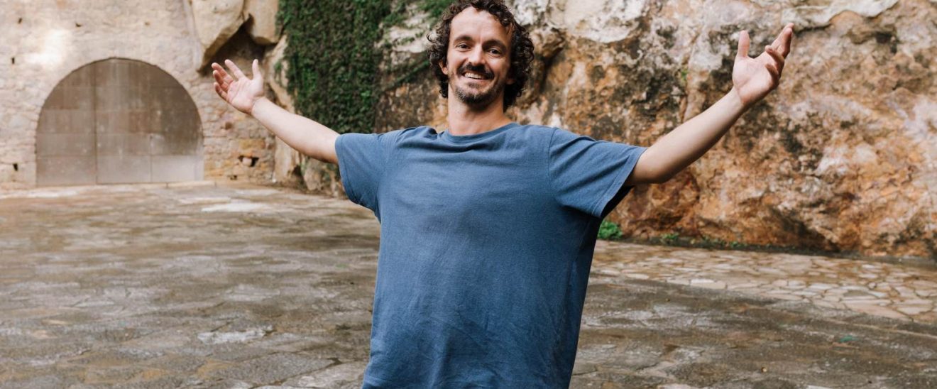 Actor sonríe con los brazos abiertos en un espacio exterior, símbolo de bienestar y crecimiento personal en terapia individual.