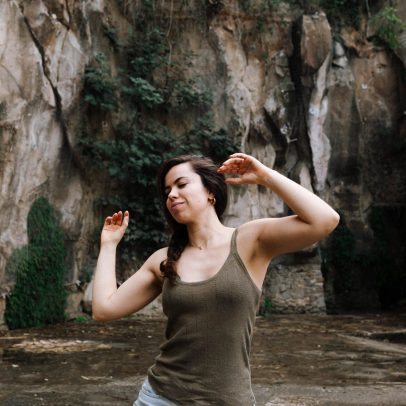 Actriz realiza un ejercicio de movimiento consciente al aire libre, con los brazos elevados, explorando expresión corporal.