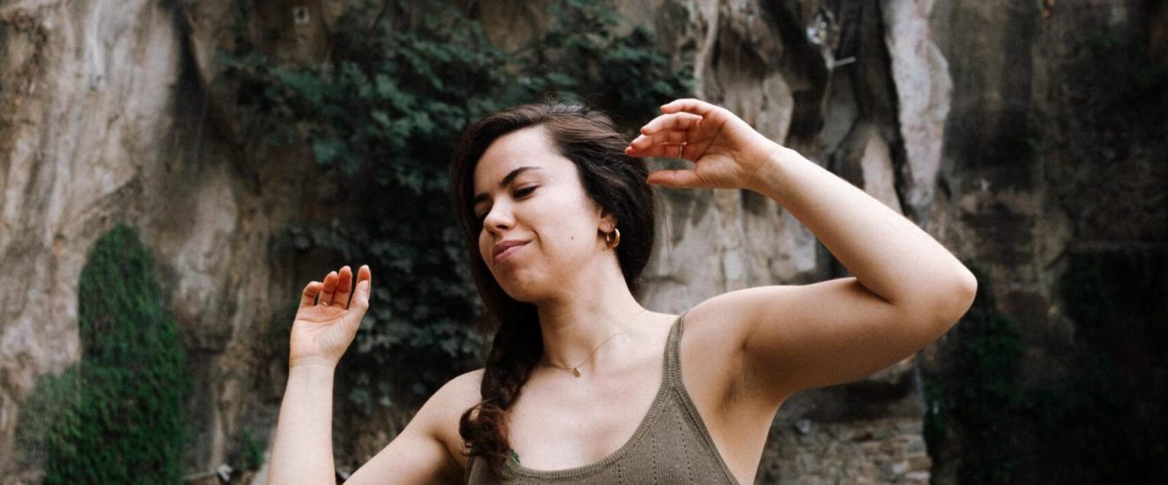 Actriz realiza un ejercicio de movimiento consciente al aire libre, con los brazos elevados, explorando expresión corporal.